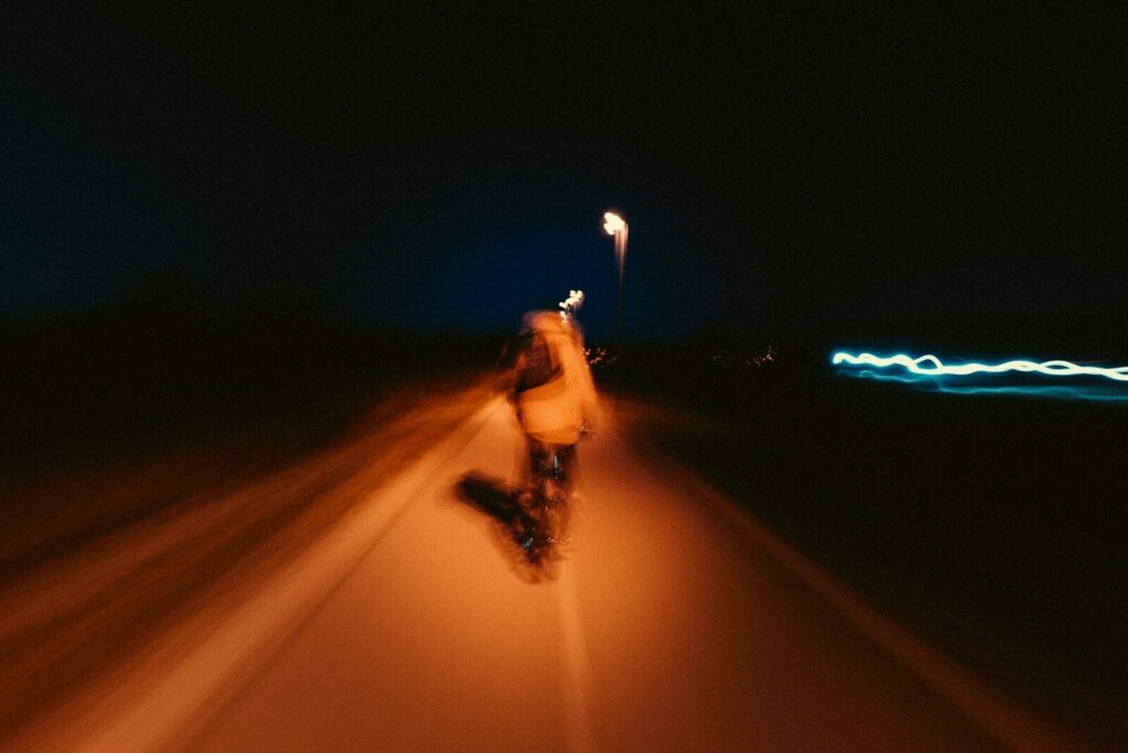 Photo by Joonas Sild a man riding a skateboard down a street at night
