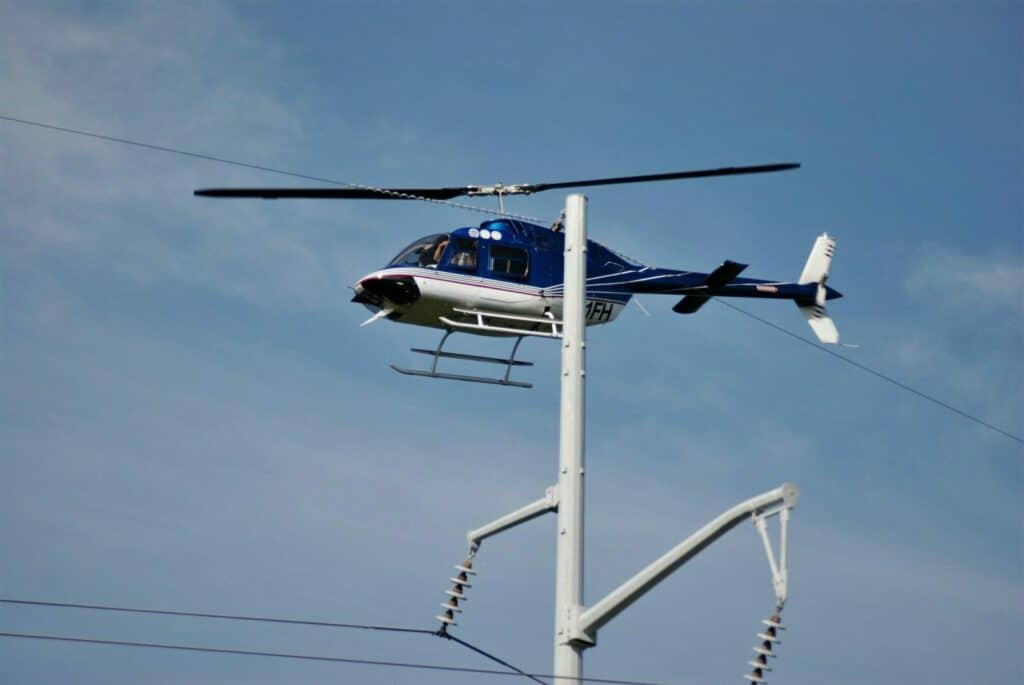 white and blue helicopter flying under blue sky during daytime